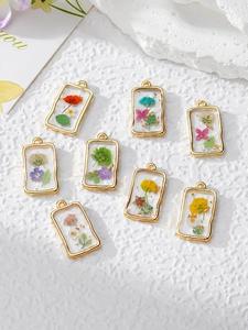 Detailed view of handmade resin flower pendants with gold frames and colorful dried petals