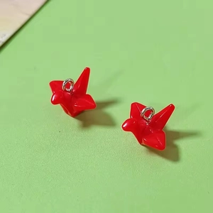 Macro shot of glossy red resin origami crane charms with silver rings for DIY jewelry