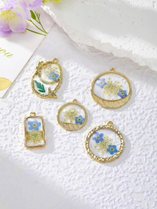 Gros plan de cinq pendentifs en fleurs séchées DIY avec cadres dorés et résine bleue