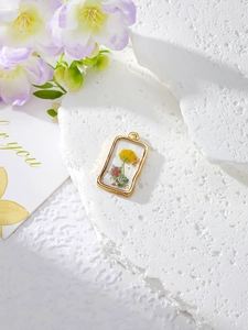 Macro detail of rectangle resin dried flower pendant with gold foil and golden edges
