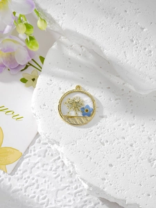Gros plan du pendentif en résine à bordure dorée avec fleurs séchées blanches et bleues