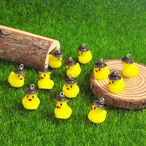 Set of 12 yellow resin duck pendants with brown hats and rings on green grass
