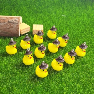 Group of 12 cute yellow duck charms with brown hats on green grass for DIY jewelry crafts