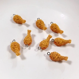 Dettaglio macro di ciondoli realistici a forma di pollo fritto con anelli per gioielli DIY