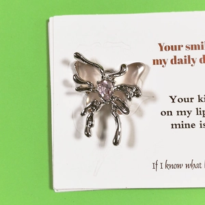 Detailed macro view of silver liquid metal butterfly pendant with pink gemstone inlay