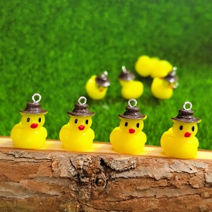 Detail of yellow resin duck charms with brown hats on a rustic wood surface for DIY crafts