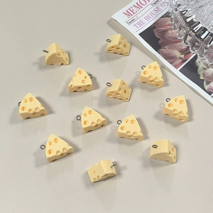 Detailed macro of 12 yellow resin cheese pendants with realistic texture and metal hooks