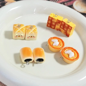 Close-up of cute resin miniature bread and egg tart charms on a white ceramic plate