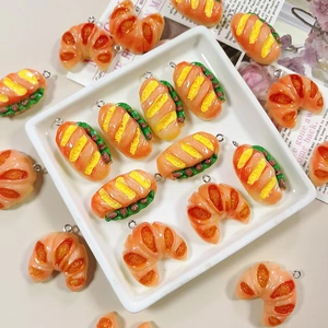 Macro shot of realistic resin bread pendants and croissant charms with metal eyelet pins