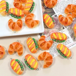 Macro detail of resin croissant and baguette charms with silver jump rings for DIY crafts