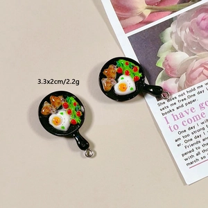 Macro view of miniature resin frying pan charm with heart egg and bacon details