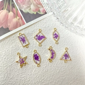 Detailed view of geometric gold alloy resin charms with purple dried flowers for DIY jewelry