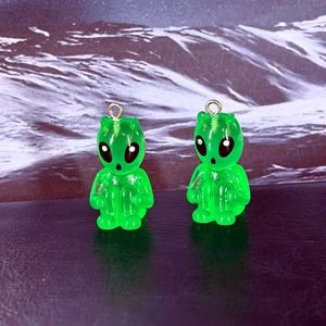 Close-up of translucent neon green resin alien charms with gold metal rings for DIY