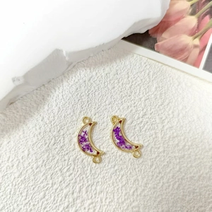 Detailed view of moon-shaped gold resin charms with purple dried flowers for jewelry DIY