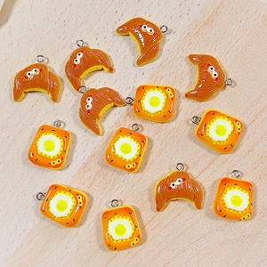 Macro shot of 3D resin bread charms with croissant and toast egg designs on wood