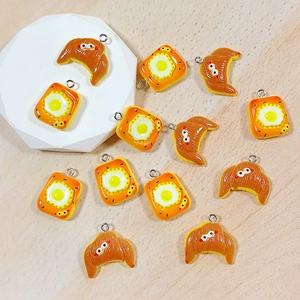 Macro shot of resin croissant and fried egg toast charms for DIY handmade jewelry crafts