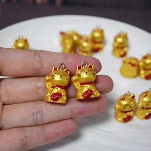 Nahaufnahme von goldenem Maneki-neko Harz-Anhänger mit rotem Halsband für DIY-Schmuck