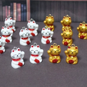 Detailansicht von Maneki-Neko-Anhängern aus Harz mit roten Schals und Glöckchen