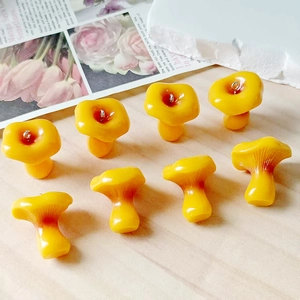 Detail of yellow resin mushroom pendants with silver loops on light wood background