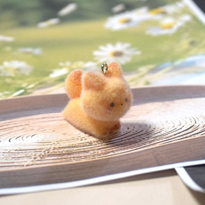 Close-up of cute orange flocked cat charm with silver metal ring on a wooden tray