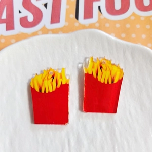 Detail of acrylic French fries pendants for DIY jewelry making on white textured plate