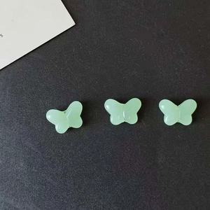 Detailed view of light green resin butterfly charms for DIY jewelry making and crafts