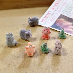 Close-up of assorted flocked animal charms like foxes and cats with metal rings for DIY