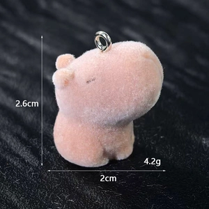 Dettaglio macro del ciondolo capibara floccato rosa con anello metallico su fondo materico