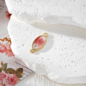 Macro view of gold oval resin charm with real pink dried flowers and double loops