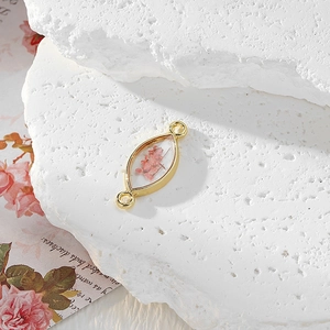 Macro detail of eye-shaped resin charm with pink dried flowers and golden frame