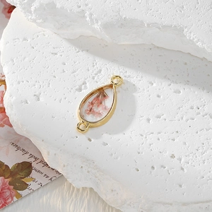 Macro view of teardrop pink dried flower pendant with gold alloy frame for jewelry DIY