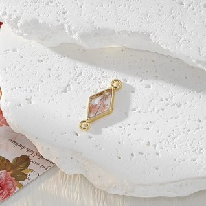 Macro detail of geometric gold pendant with real pink dried flowers in resin for DIY
