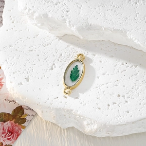 Détail du pendentif doré ovale avec véritable feuille verte pour création bijoux
