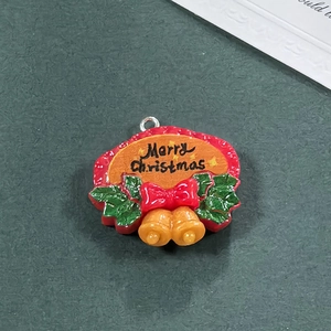 Dettaglio pendente natalizio in resina con testo Merry Christmas e piccole campane