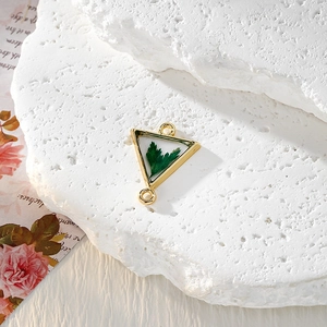 Gros plan d'un pendentif triangle doré en résine avec de vraies feuilles vertes