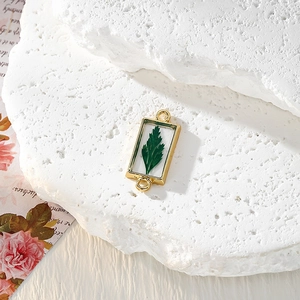 Vue macro détaillée d'un pendentif rectangulaire doré en résine avec une feuille naturelle