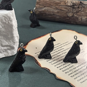 Detail of raven resin charms with yellow eyes and silver loops for DIY jewelry