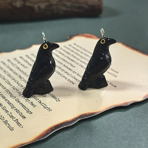 Detail of gothic black resin raven pendant with yellow eyes on vintage paper background