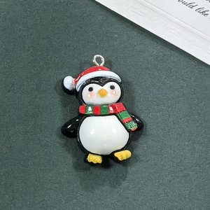 Dettaglio di un ciondolo a pinguino di Natale in resina con cappello rosso per gioielli DIY