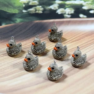 Macro detail of punk resin duck skull pendants on a wooden tray for DIY jewelry making