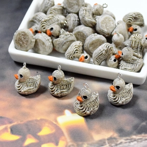 Macro detail of resin skeleton duck pendants with orange beaks for Halloween DIY crafts