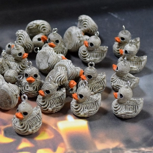 Macro detail of mummy-style skull duck charms with orange beaks for Halloween DIY crafts