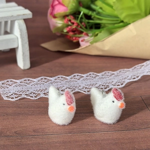 Detail of white flocked chick pendants with red combs for DIY jewelry and crafts