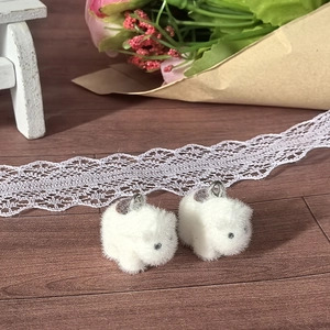 Close-up of white flocked rabbit pendants with silver rings for DIY jewelry making