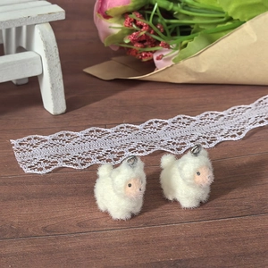 Macro shot of two cute white flocked lamb charms with metal loops for DIY jewelry making