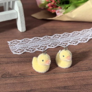 Close-up of yellow flocked duckling charms with silver rings for DIY accessories