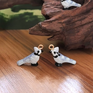 Close-up of bird resin charms with gold rings on a rustic wooden background