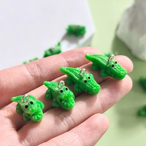 Mini-Krokodil-Anhänger aus Harz mit Silberringen für DIY-Schmuck in der Hand