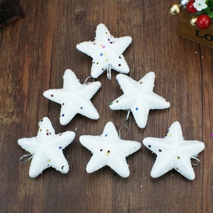Set of 6 white foam Christmas star ornaments with colorful sequins on dark wood