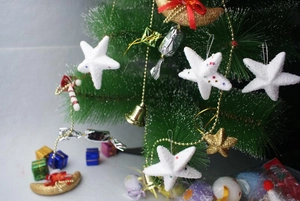 White foam stars and glitter moon ornaments hanging on a festive Christmas tree branch